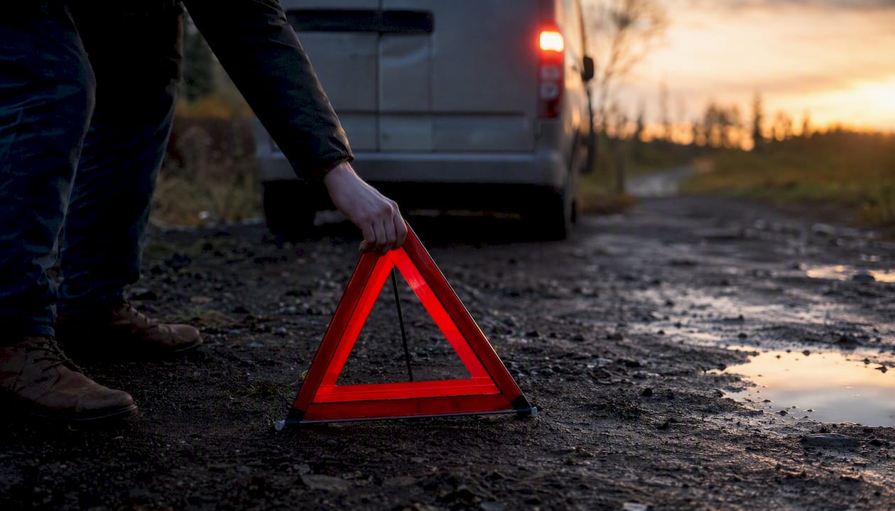 Hand placing warning triangle behind off-road van
