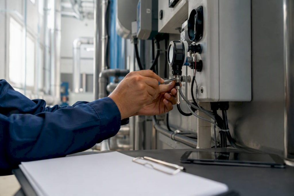 Technician adjusting industrial sensor in plant room