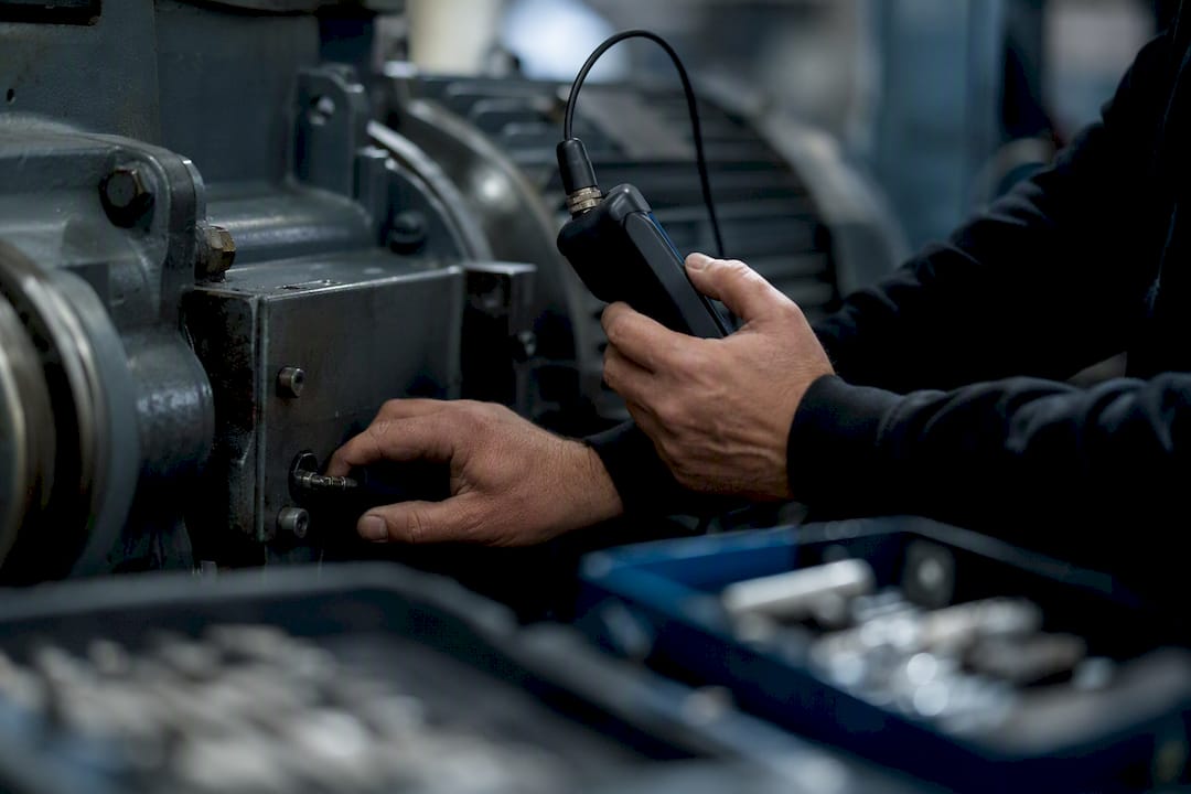 Hands using vibration sensor on machinery