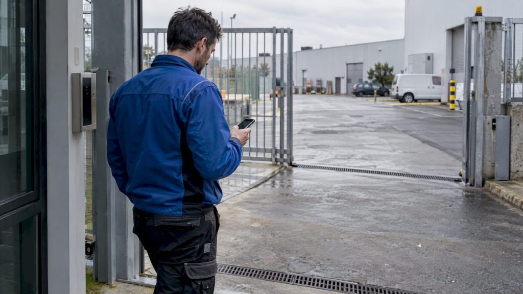 Technician checking phone at an industrial site entrance